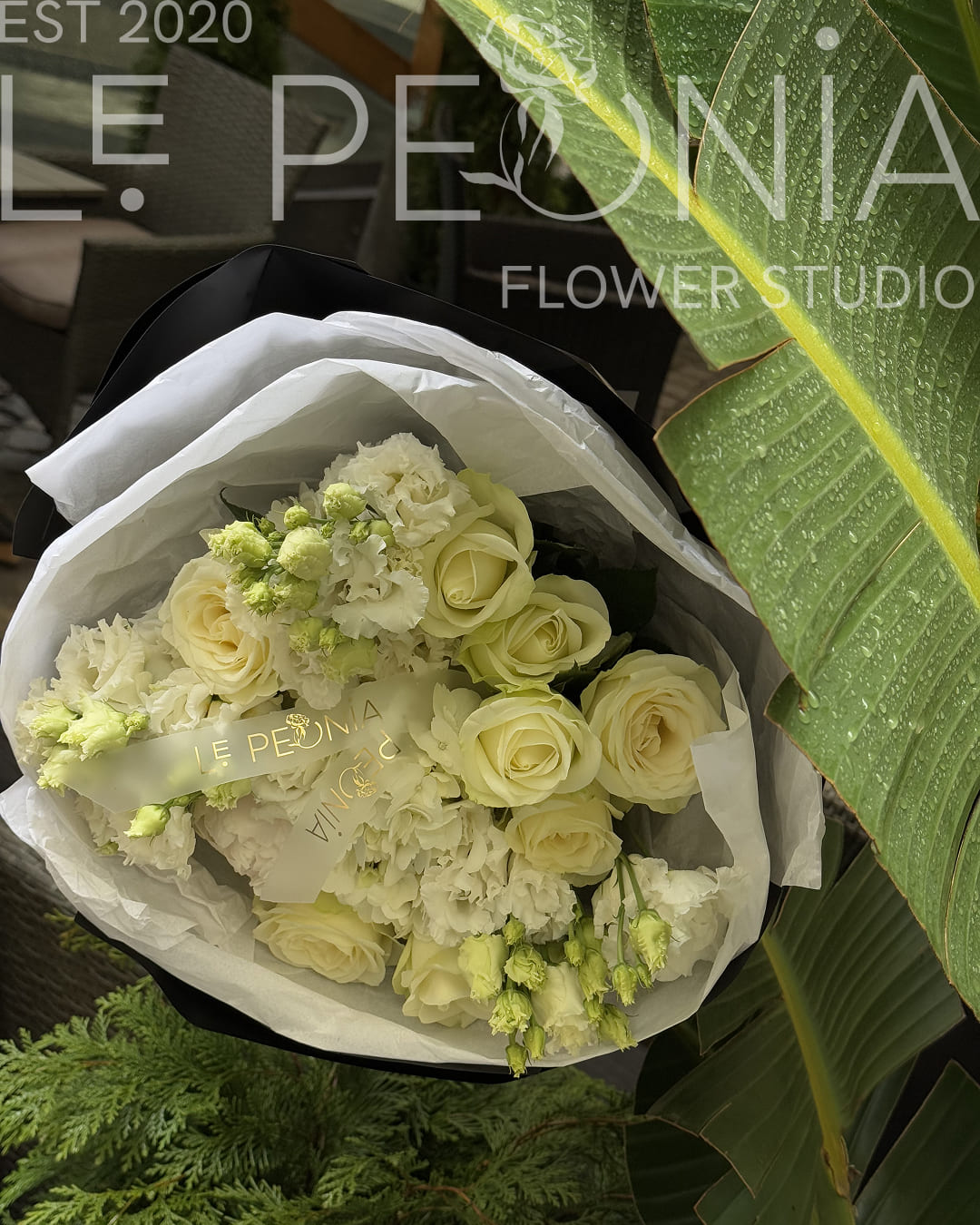 Elegant bouquet with white roses, lisianthus and eustoma buds, wrapped in black and white paper with satin Le Peonia ribbon