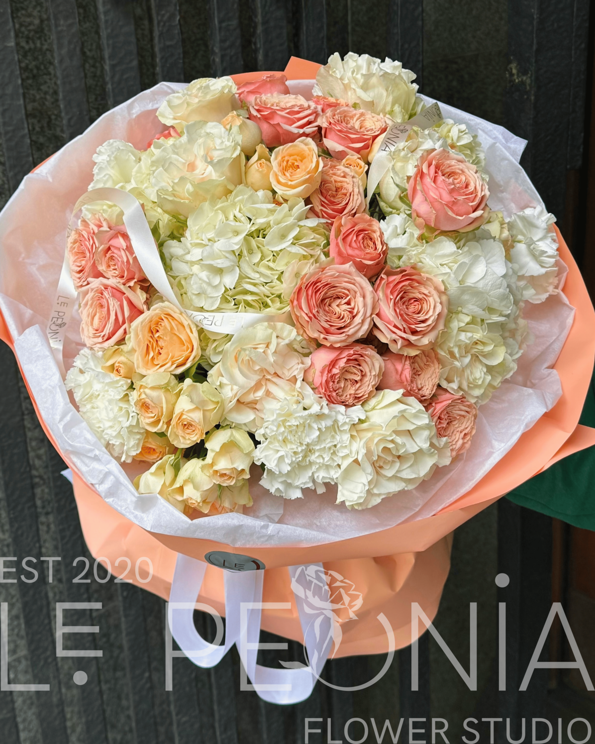 Peach roses, voluminous hydrangea and soft carnations in peach-tone wrap