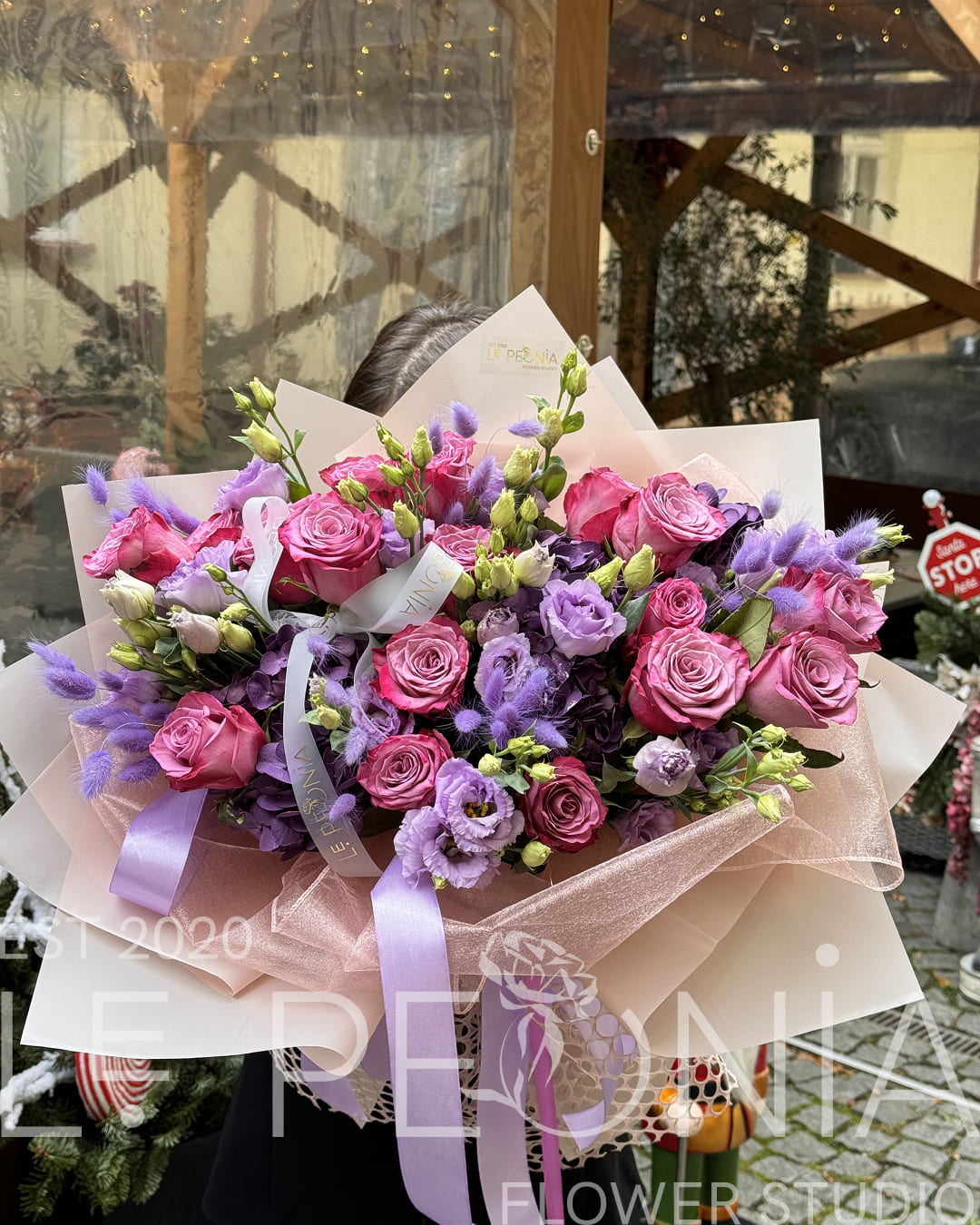 Bold bouquet in pink and purple tones with roses, lisianthus and fluffy lavender lagurus, wrapped in pearlescent and matte paper with lilac ribbons
