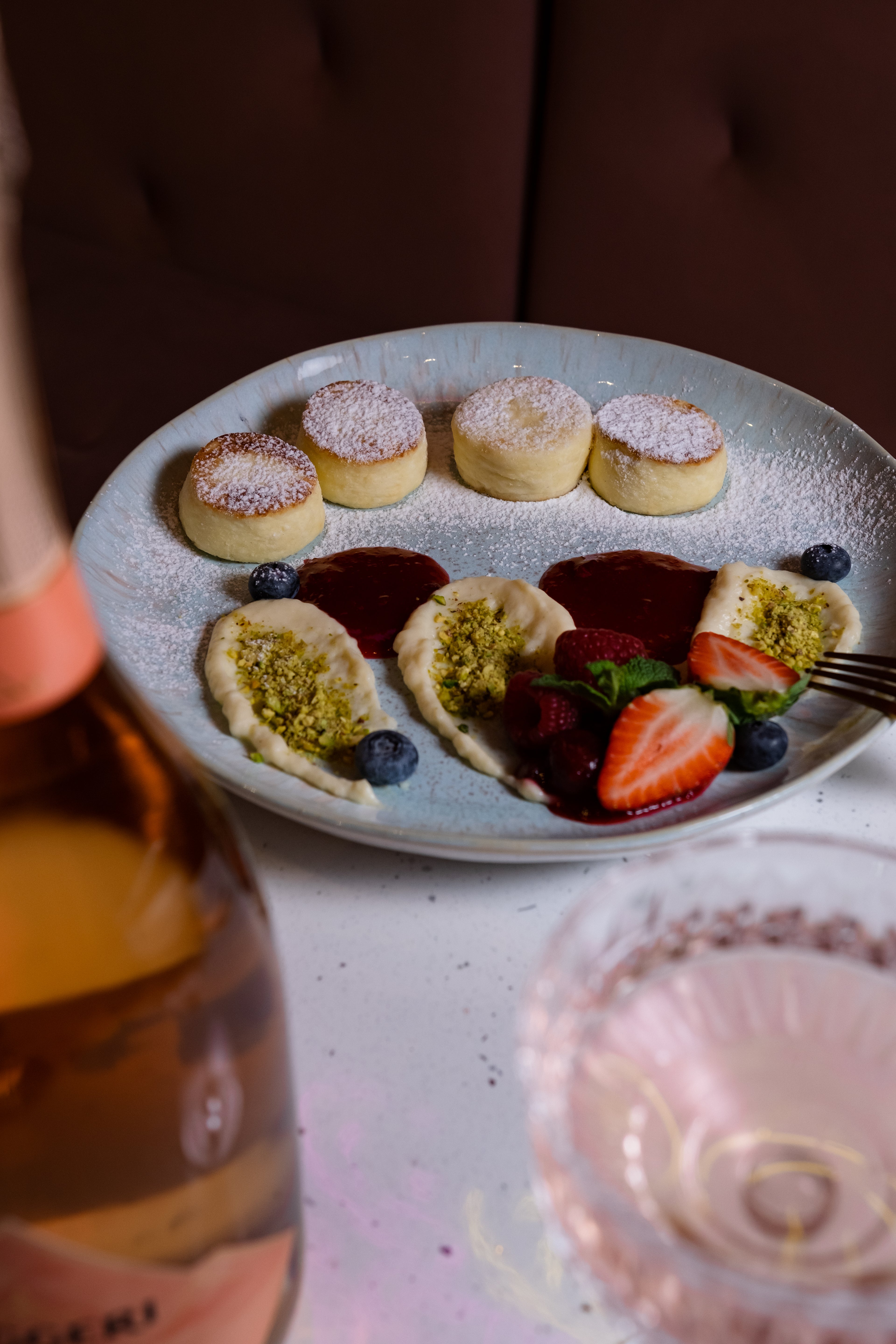 Assorted pastries on a plate with a bottle of rosé wine in the foreground.